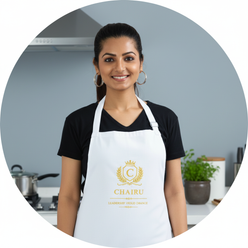 Portrait of smiling South Asian woman, Ishita Das, wearing a heavyweight cotton drill apron in a modern kitchen.
